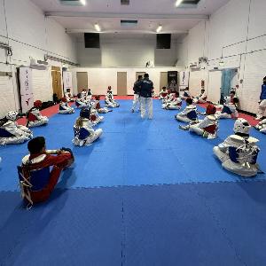 Students stretching in a circle with the coach at the centre